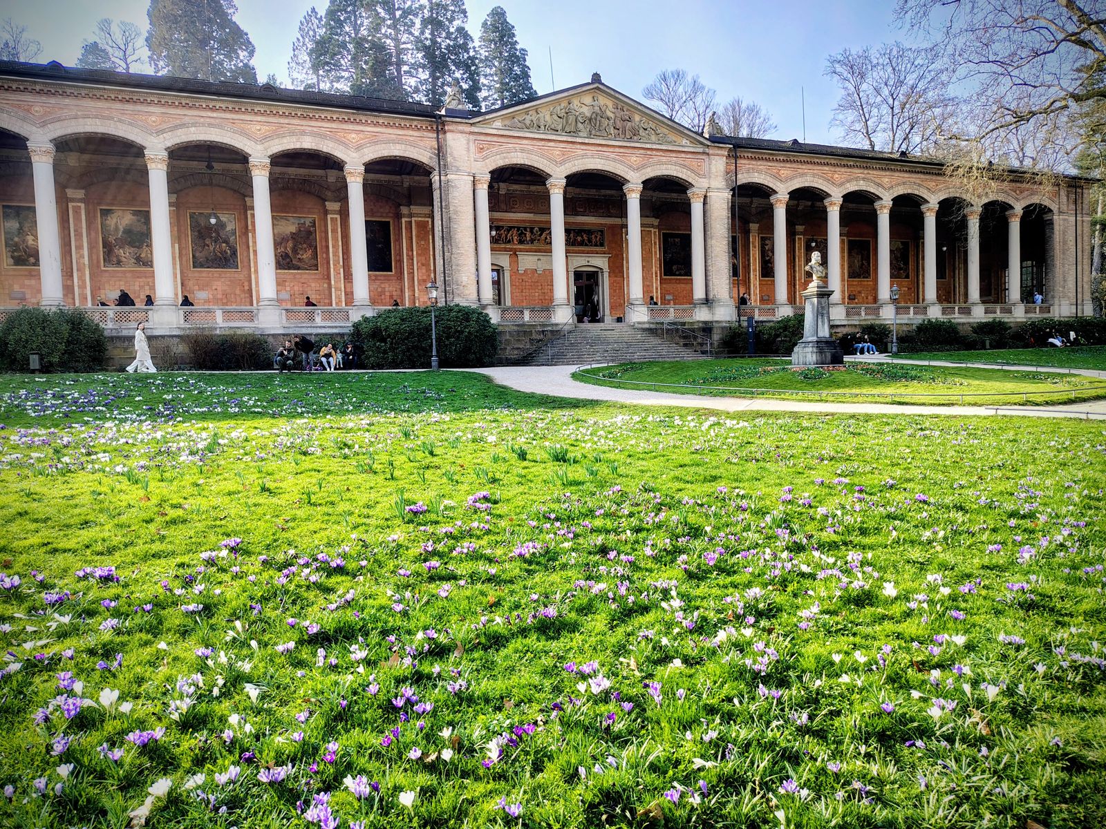 The Trinkhalle colonnade and its painted arcades, crocuses out across the lawn