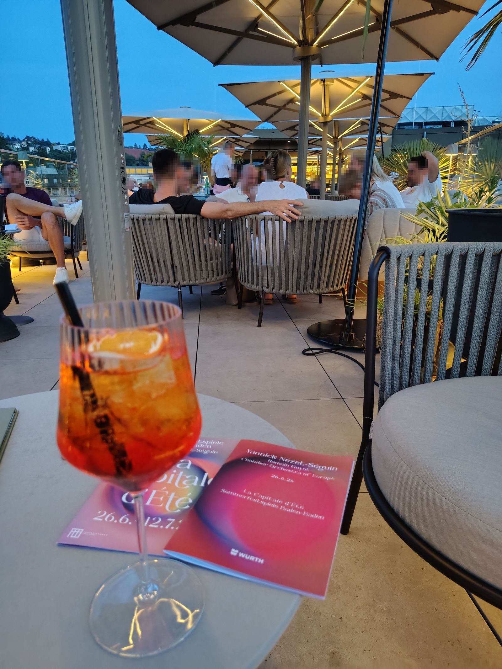 A spritz on the Steigenberger roof terrace at dusk, the Festspielhaus programme open on the table