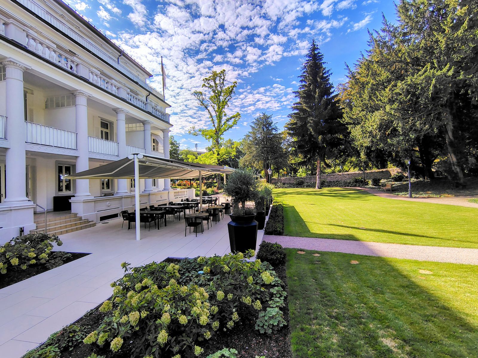 The Badischer Hof garden frontage on a bright morning, the lawn running down to the trees