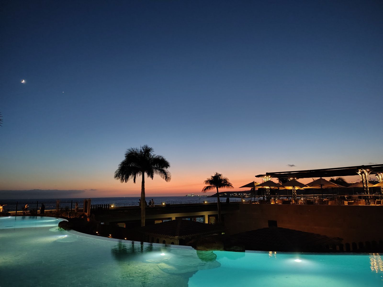 A single palm against the last of the light, the Lopesan pool still warm