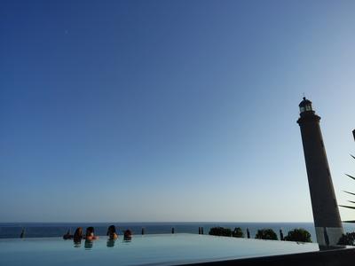 The infinity pool at Hotel Faro, a Lopesan Collection Hotel — the Maspalomas lighthouse right beside it, which is where the hotel gets its name