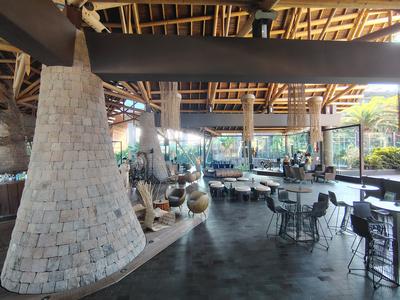 The Lopesan Baobab atrium in daylight — stone chimneys, woven lampshades and a stage at the far end