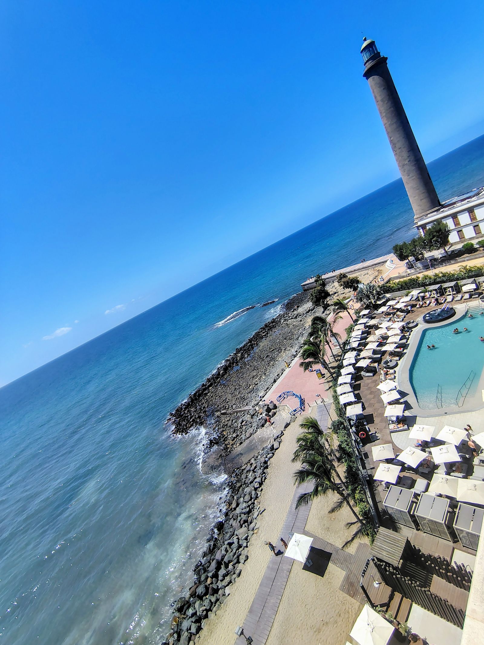 The whole strip from above: pools, promenade, and the lighthouse holding the end of it
