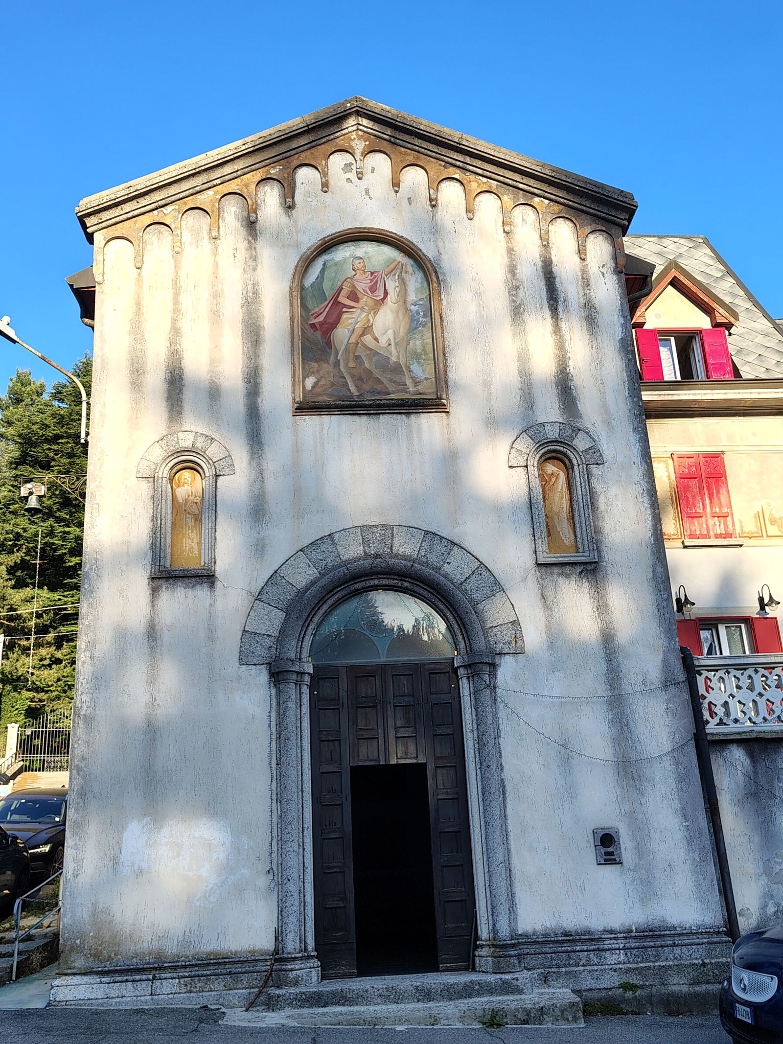 A small white church above the road, eleventh-century underneath the paint
