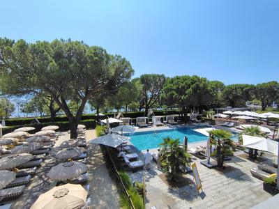 A pool terrace under the umbrella pines at Ouchy, cabanas and all