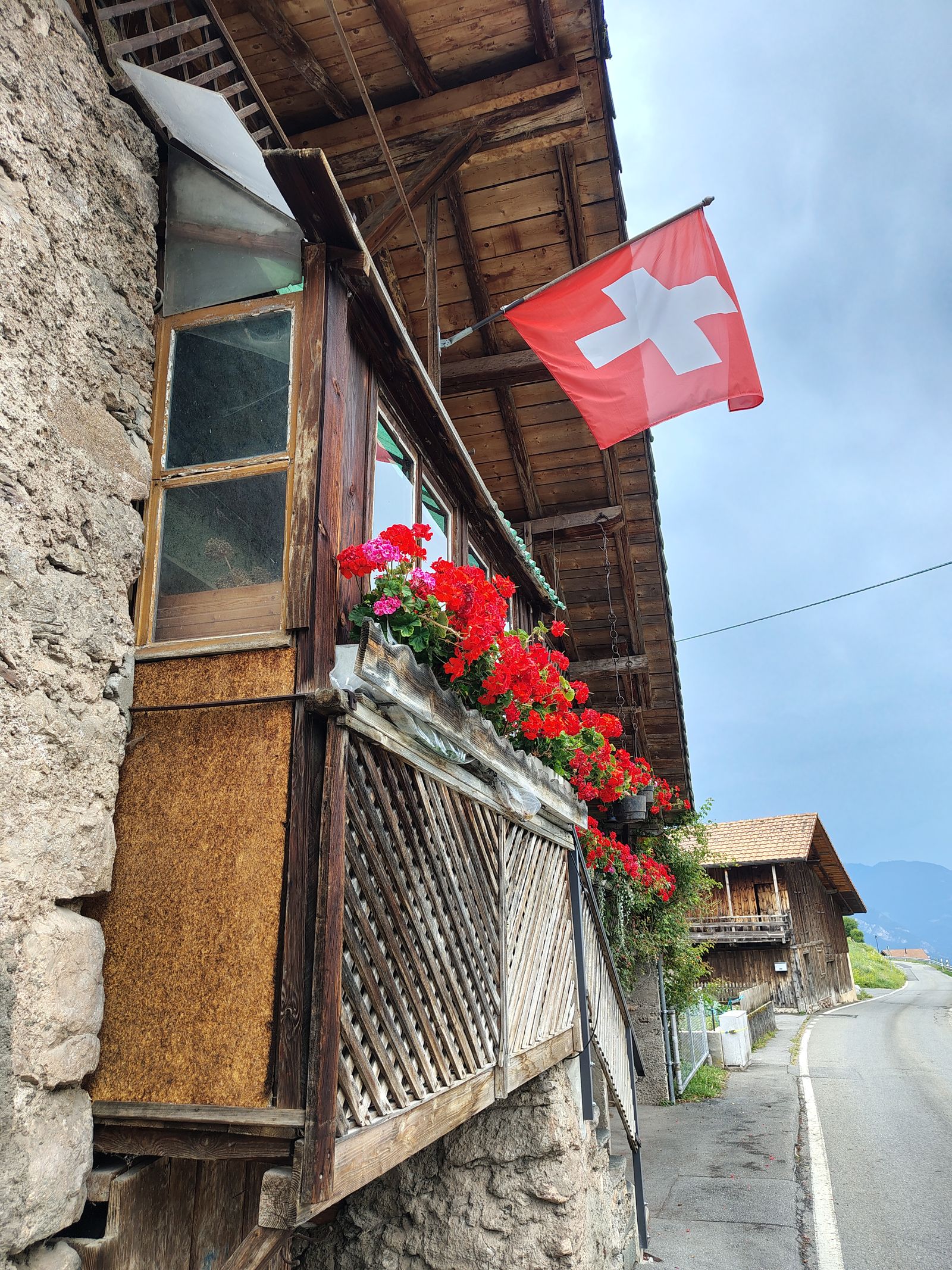 Geraniums and a flag on a chalet balcony, which is not a cliché if it is simply there
