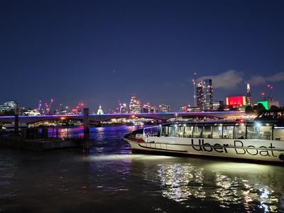 A river bus on the Thames at night, the City and St Paul's lit up behind