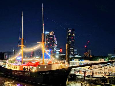 A tall ship turned bar at Temple Pier, the City towers behind