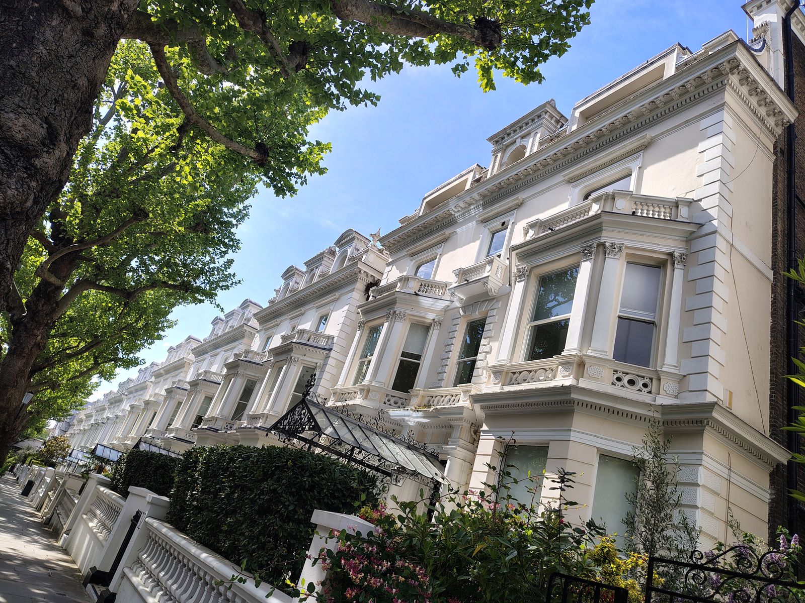 White stucco villas on a tree-lined street in Holland Park