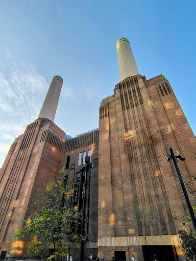 Two of Battersea's four chimneys from directly below, brick and evening sun — London