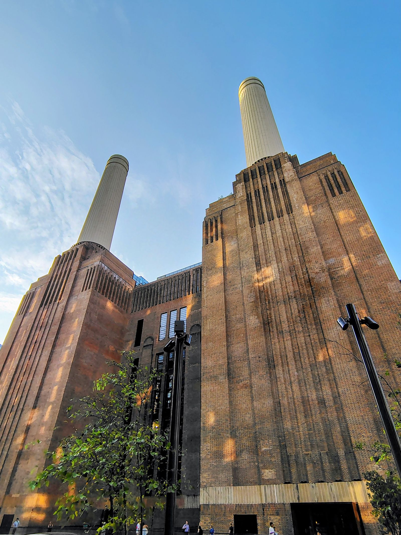 Two of Battersea's four chimneys from directly below, brick and evening sun