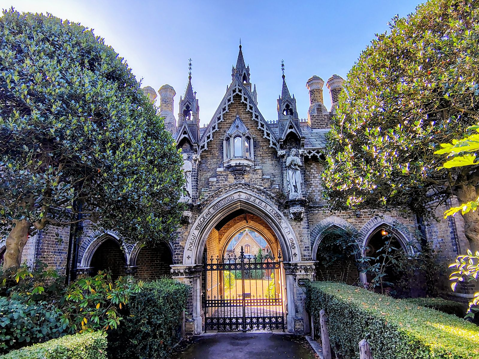 The gothic gateway into Highgate Cemetery, framed by clipped trees