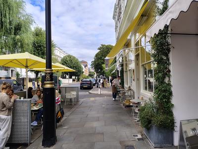 Yellow awnings and pavement tables on a side street, the version of London people actually live in