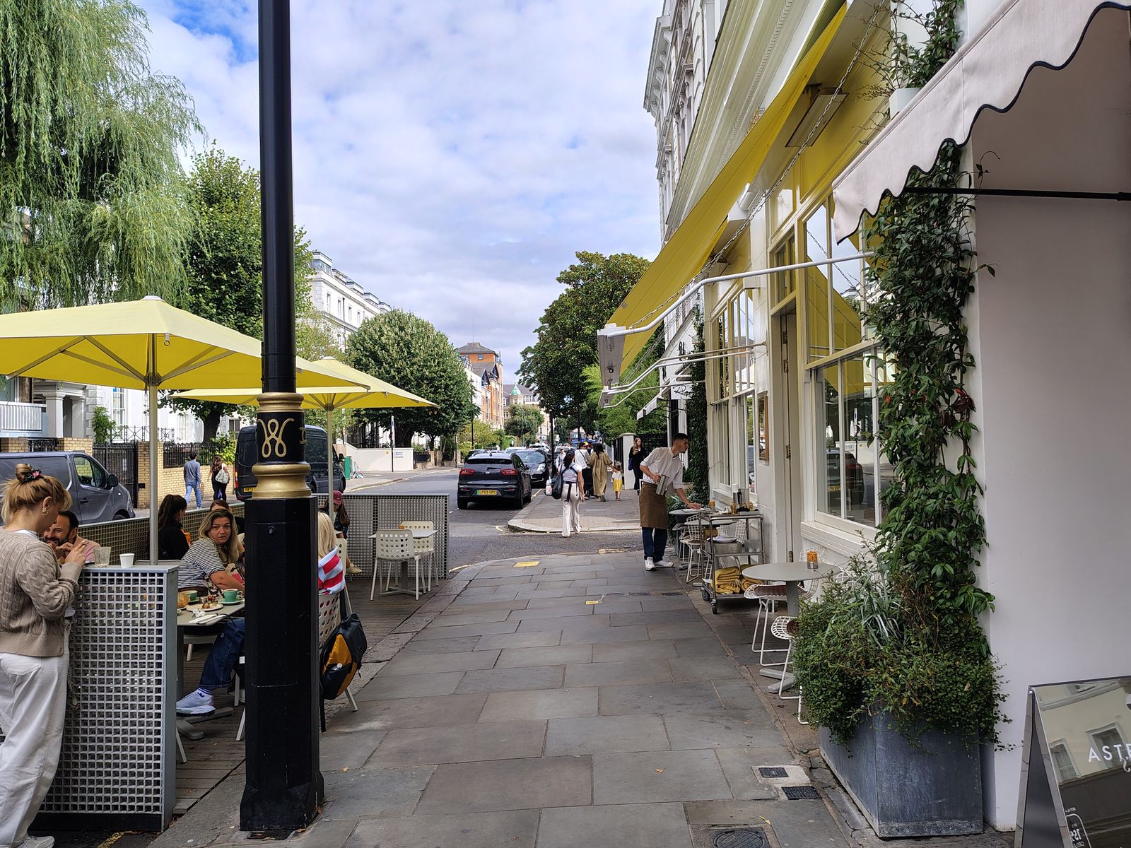 Yellow awnings and pavement tables on a side street, the version of London people actually live in