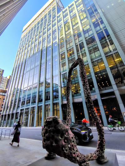 A bronze sculpture on a City pavement under glass towers