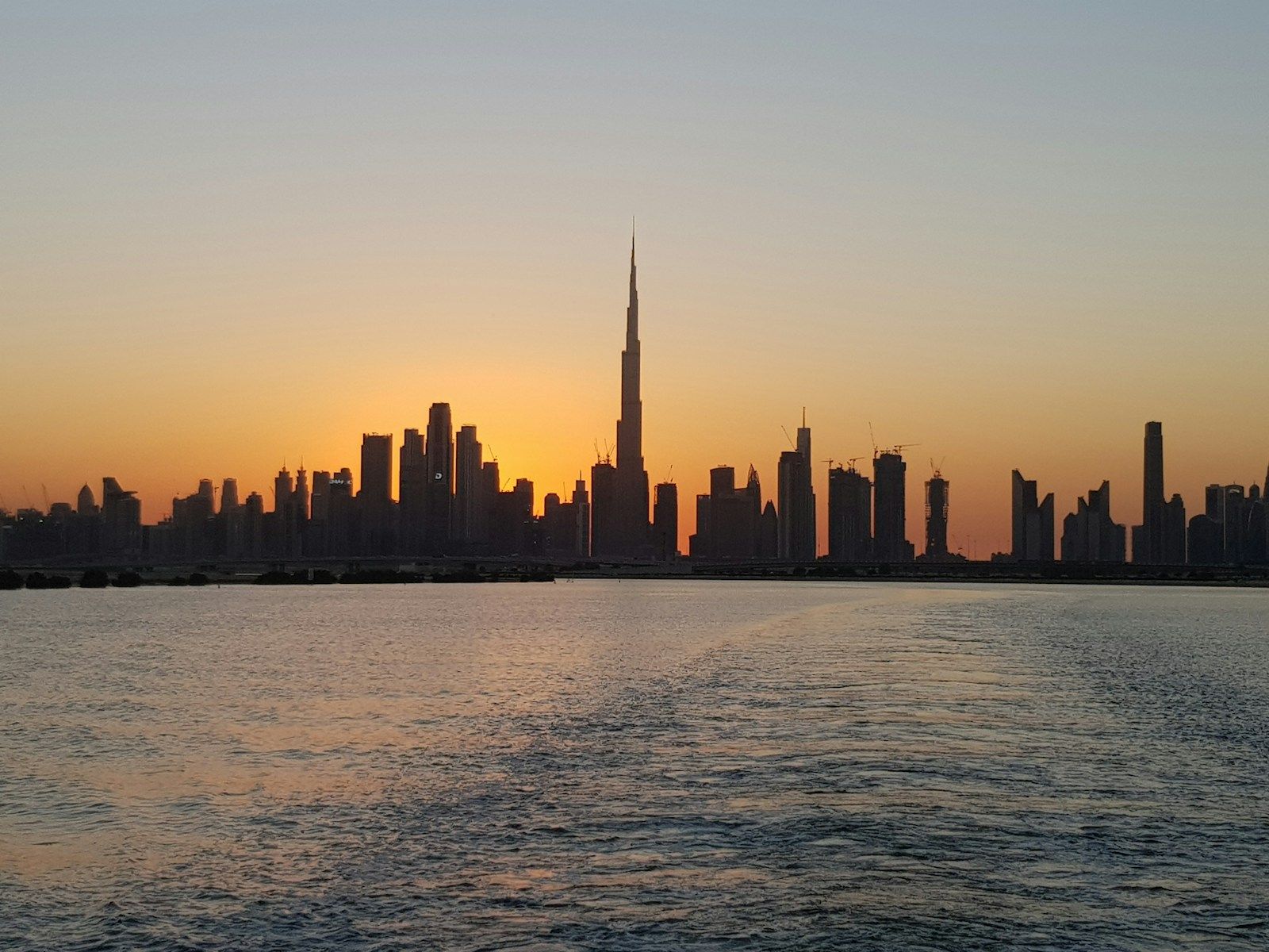 The skyline across the water at sunset — Dubai